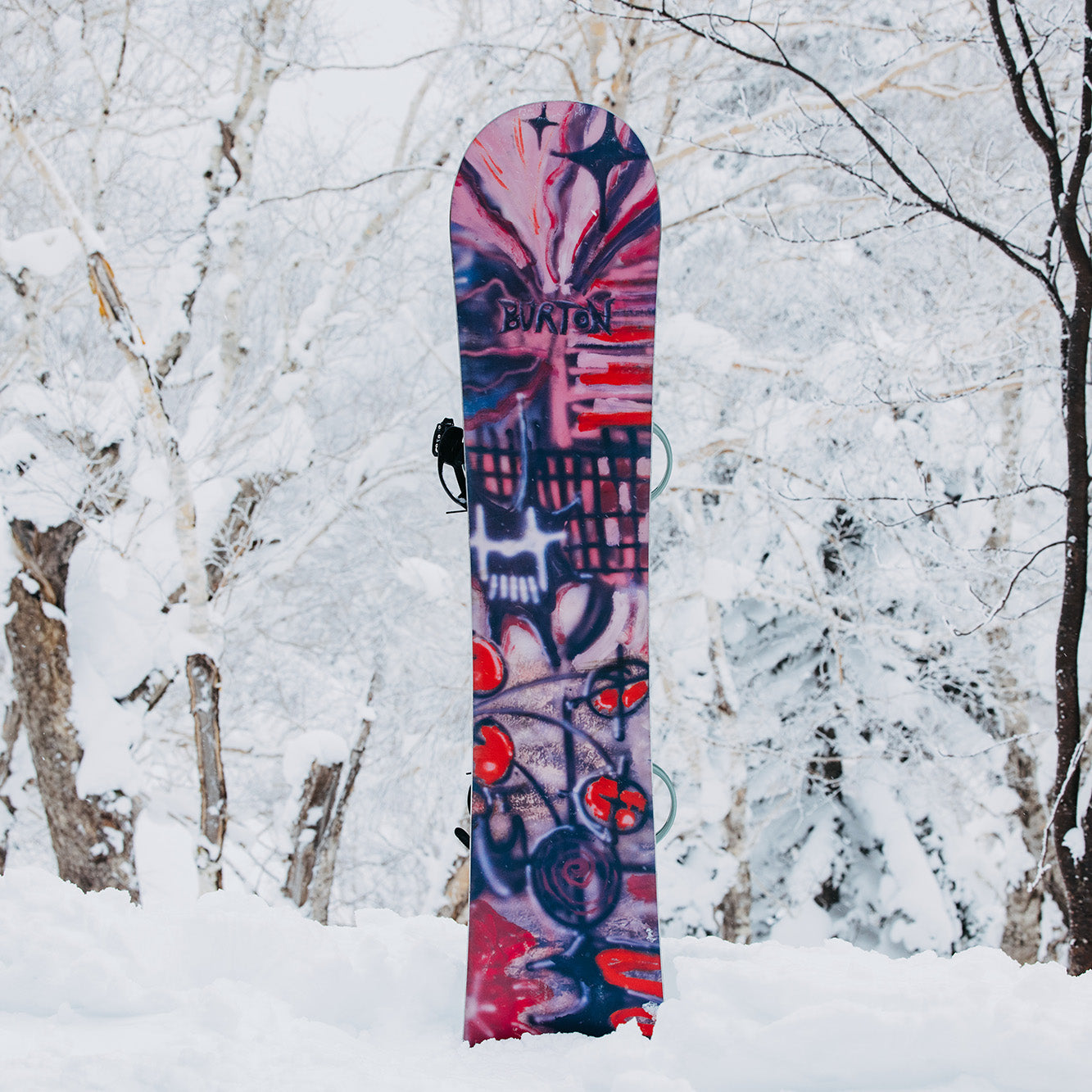 A men's snowboard, the Burton Blossom 2025 Snowboard, in the snow.
